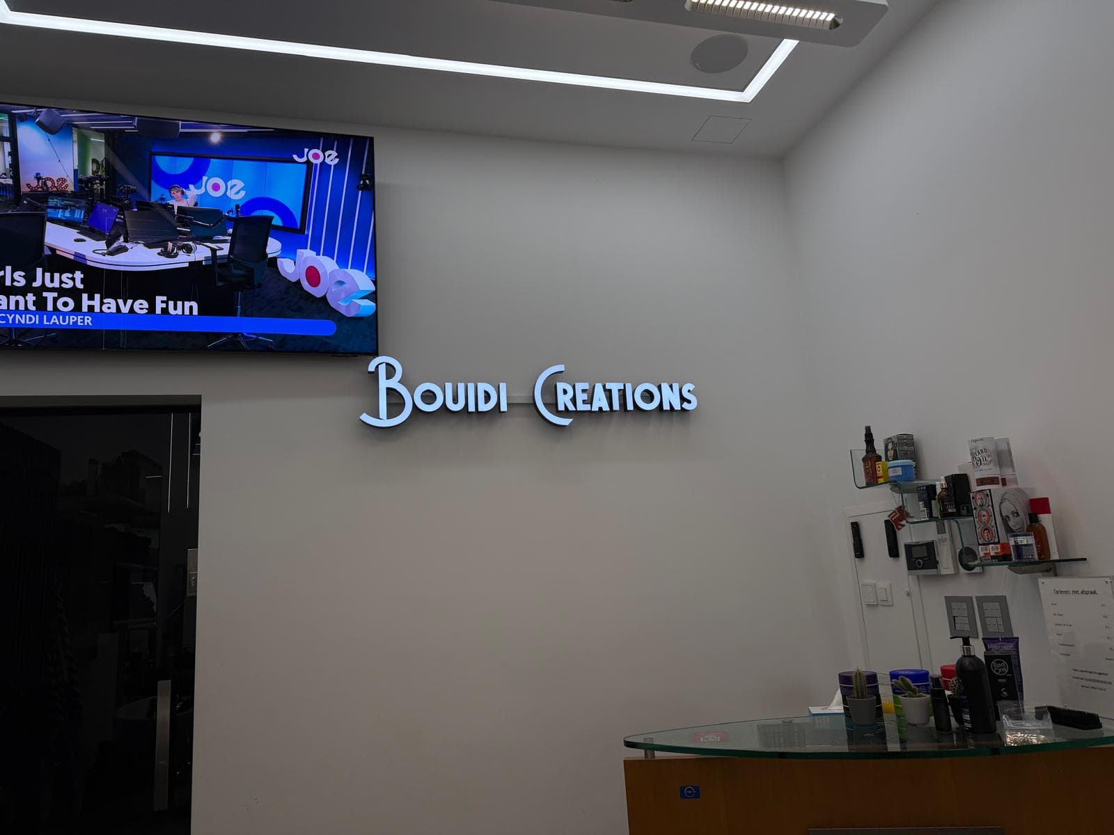 Het lichtbord Bouidi Creations aan de muur van de zaak